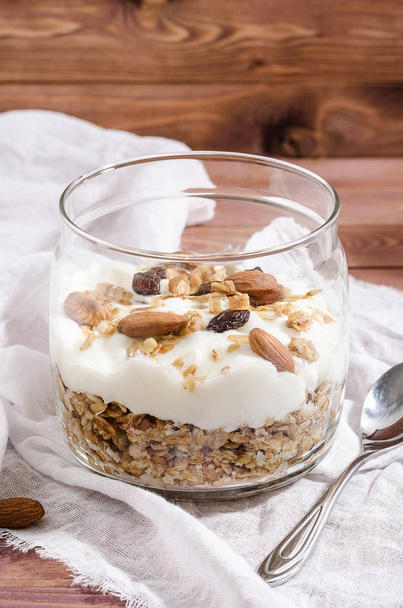 muesli with natural yoghurt, nuts and dried fruits in a glass jar - 写真・画像