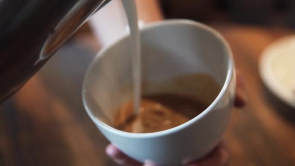 waiter pours a latte or cappuccino into a glass - Felvétel, videó
