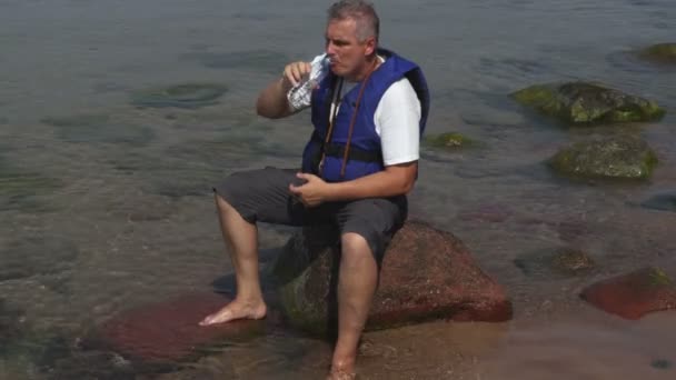 Homem de colete salva-vidas bebe água
 - Filmagem, Vídeo