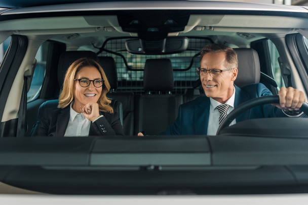 smiling business couple sitting in new car for test drive - Fotó, kép