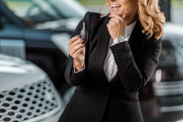 ritagliato colpo di donna d'affari sorridente che tiene chiave dell'automobile allo showroom
 - Foto, immagini
