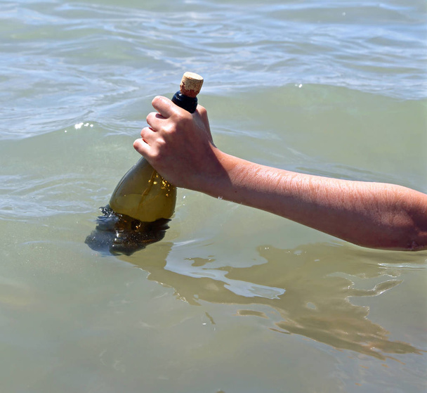 mano dell'uomo che prende una bottiglia con un messaggio segreto nell'oceano
 - Foto, immagini