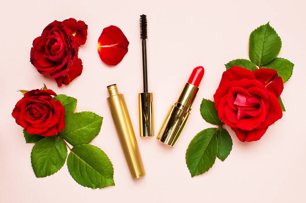 Διάφορα προϊόντα μακιγιάζ με κόκκινα τριαντάφυλλα σε ροζ φόντο με αντίγραφο επάνω χώρο δείτε επίπεδη θέσει γυναικεία πράγματα - Φωτογραφία, εικόνα