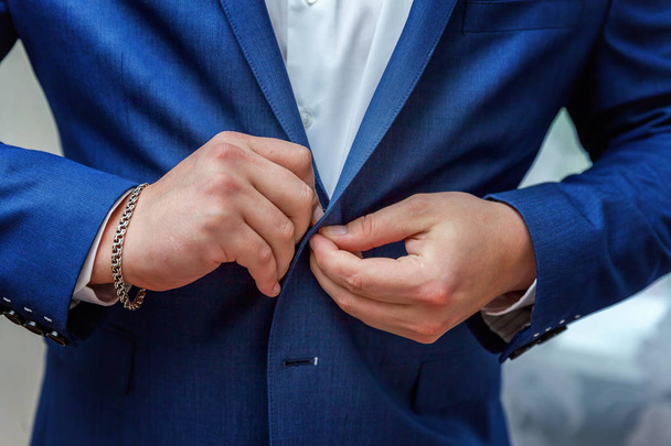 Empresario lleva una chaqueta, manos masculinas primer plano, novio preparándose en la mañana antes de la ceremonia de boda
 - Foto, Imagen