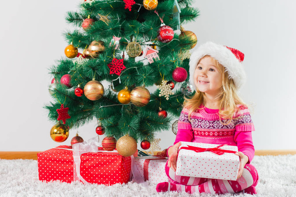 Gelukkig Kerstmis kind met gift box en Nieuwjaar boom thuis. - Foto, afbeelding