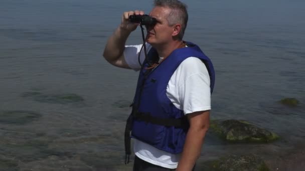 Man op de zee kijkt de verrekijker in zomerdag - Video