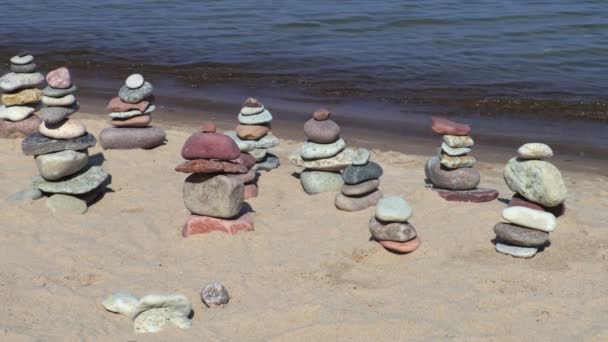 Pirámides de piedras equilibradas en la playa en el día de verano
 - Imágenes, Vídeo