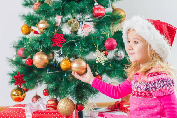 Happy Christmas child with gift box and new year tree at home. - Photo, Image