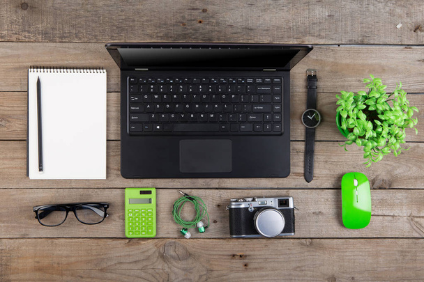 Χώρος εργασίας από ψηλά - laptop, σημειωματάριο, γυαλιά και κάμερα στο ξύλινο γραφείο - Φωτογραφία, εικόνα