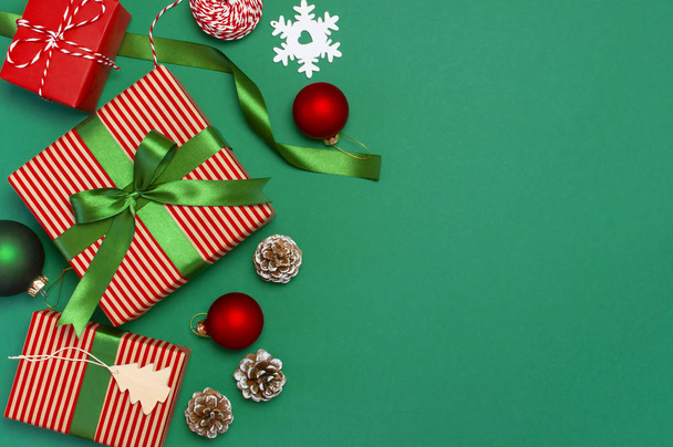 Dárkové krabice, hračky, vánoční koule, jedle kavkazská, stuha na zeleném pozadí. Slavnostní, blahopřání, novoroční vánoční dárky vánoční 2019 svátečními pozdravy. Plochá ležel, horní pohled - Fotografie, Obrázek