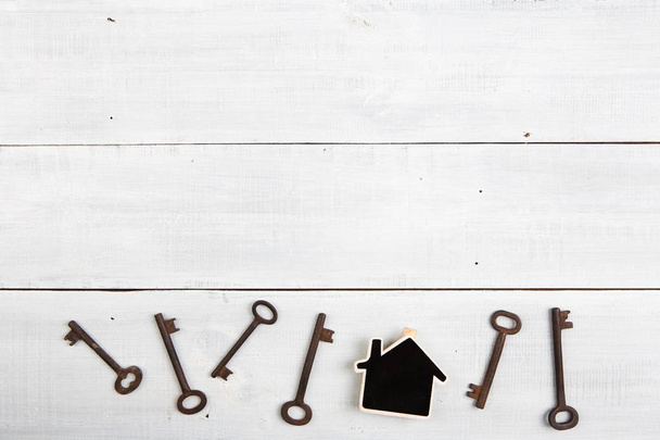 Immobilienkonzept - Haus und Schlüssel auf weißem Holztisch - Foto, Bild