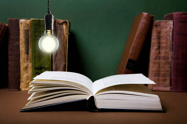 Open book on the desk under the incandescent bulb - Foto, immagini