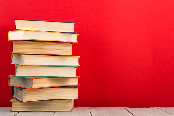 education and wisdom concept - books on wooden table, red background - Photo, image
