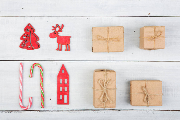 Weihnachtsdekoration auf Holztisch - Weihnachtsbaum, Häuser, Engel, Hirsche, Süßigkeiten, Geschenke, Süßigkeiten - Foto, Bild