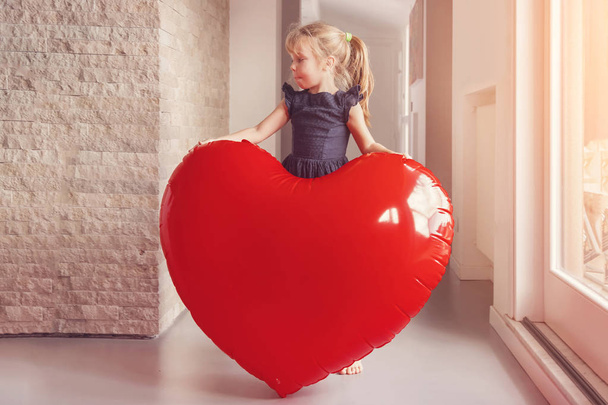 kleines blondes Mädchen mit einem großen roten Luftballon in Herzform - Foto, Bild