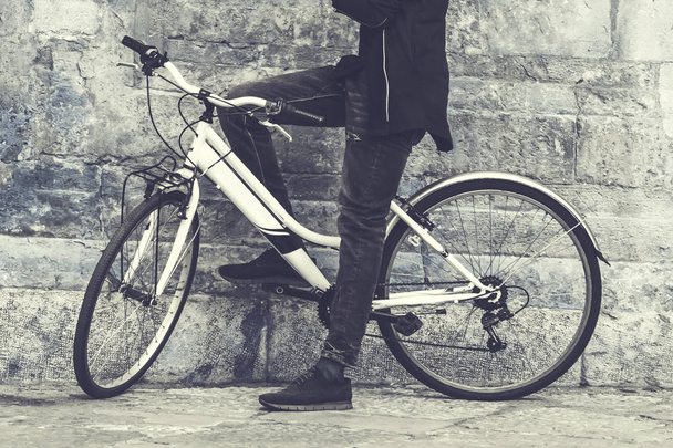 A man on a bicycle standing near a wall. Toned - Zdjęcie, obraz