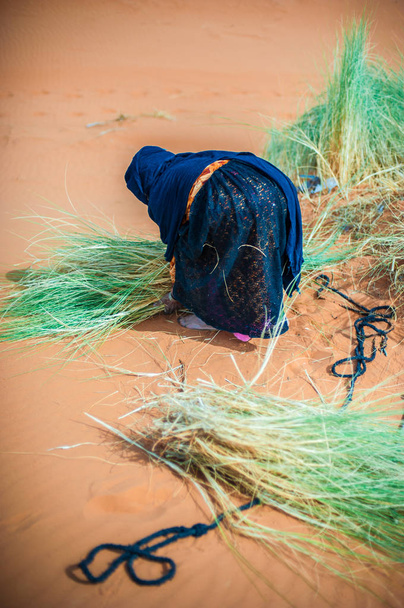 古いベルベル人女性仕事モロッコのメルズーガの砂丘に単独で - 写真・画像