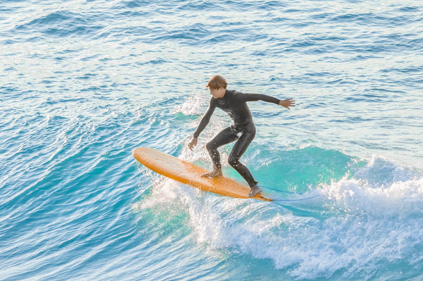 Bogliasco, Italy, October 6, 2017:  Surfer on a yellow surfboard riding a wave - Fotografie, Obrázek