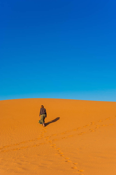 Girl walk in Erg Chebbi Desert, Sahara Desert near Merzouga, Morocco - Photo, image