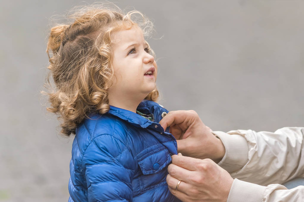 Roma, Italië, 21 oktober 2017: Een man een blauwe jas dichtknopen voor een schattig klein blond meisje  - Foto, afbeelding