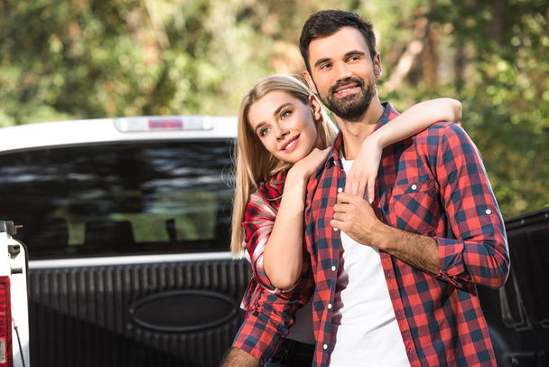 selective focus of young couple embracing each other on car trunk outdoors  - Photo, Image