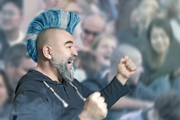 Apoiante desportivo emocional com corte de cabelo Iroquois nas cores da bandeira da Escócia durante um jogo de futebol ou futebol no estádio
 - Foto, Imagem
