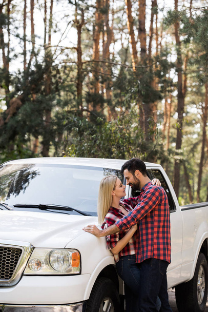 beautiful couple going to kiss near pickup truck in forest - Foto, Imagem
