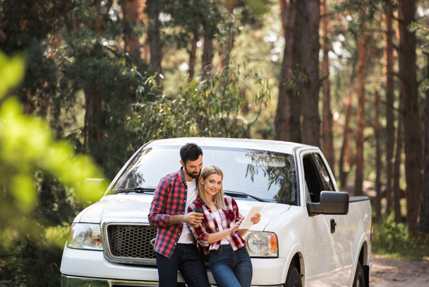 happy couple using digital tablet near pickup truck in forest - Zdjęcie, obraz