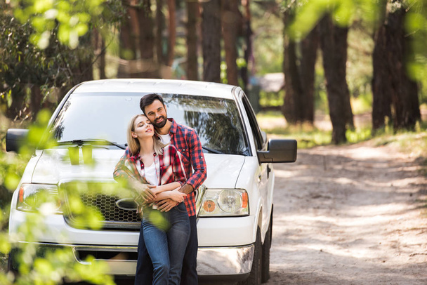 young couple embracing near pickup truck in forest - Foto, immagini