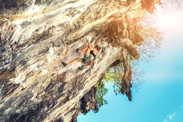Μια γυναίκα ορειβάτη σκαρφαλώνει σε γκρεμό χωρίς εξοπλισμό ασφαλείας σε μια ηλιόλουστη μέρα - Φωτογραφία, εικόνα