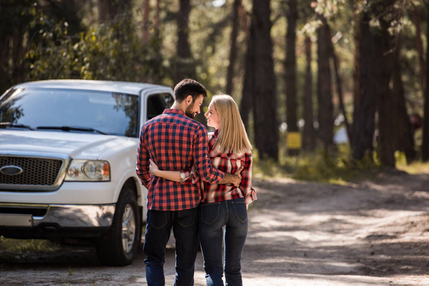 vista trasera de la pareja abrazando y caminando a camioneta en el bosque
 - Foto, imagen