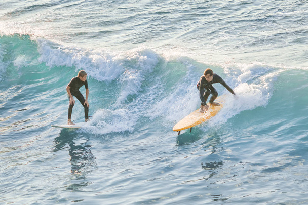 Bogliasco, Italy, October 6, 2017:  Two surfers man and woman riding on the wave - Valokuva, kuva
