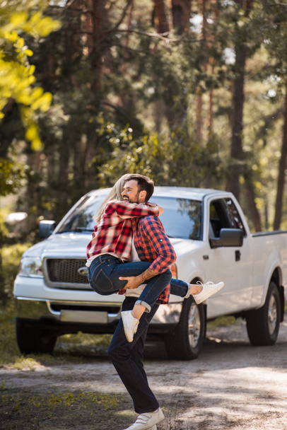 excited couple having fun together in forest with pickup truck behind - Valokuva, kuva