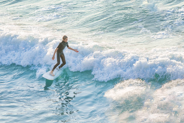 Bogliasco, Italy, October 6, 2017: Woman surfer on a white surfboard riding a wave - Foto, Bild