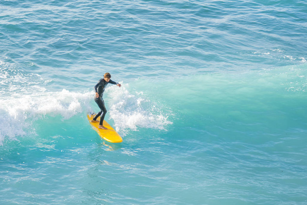 Bogliasco, Italy, October 6, 2017:  Surfer on a yellow surfboard riding a wave - Photo, image