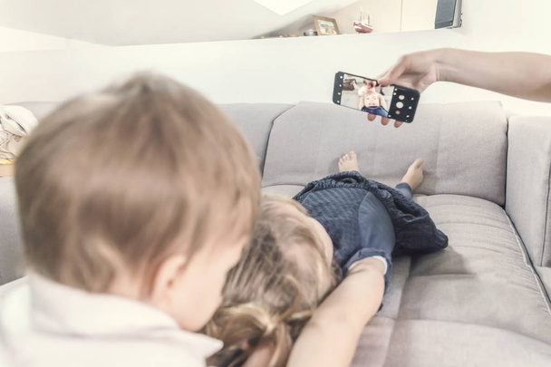 Two children lie on the couch and looking at a smartphone - Foto, Imagem