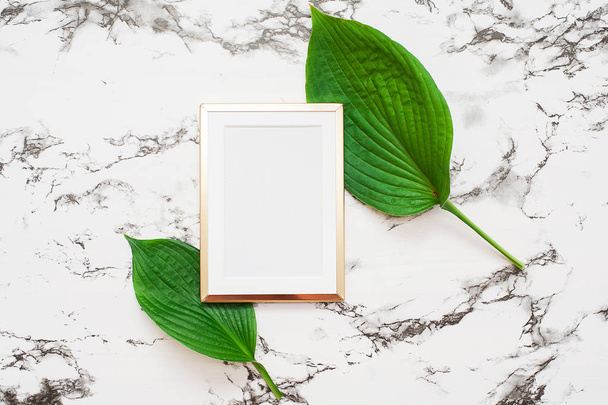 Gold photo frame with tropical leaves on marble background. Mock up frame with copyspace. Flat lay, top view. - Fotoğraf, Görsel