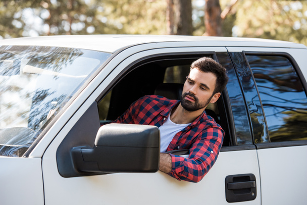 serious bearded man driving pickup truck in forest - Photo, Image