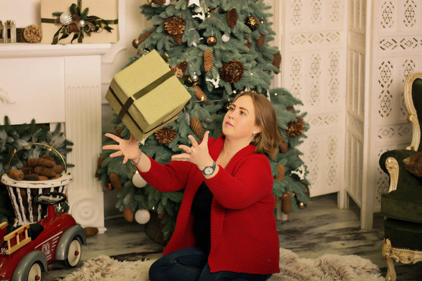 beautiful young woman with gift box near christmas tree - 写真・画像