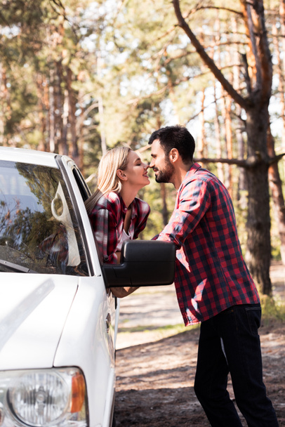 mies menossa suudella onnellinen tyttöystävä, kun hän istuu pickup kuorma metsässä
 - Valokuva, kuva