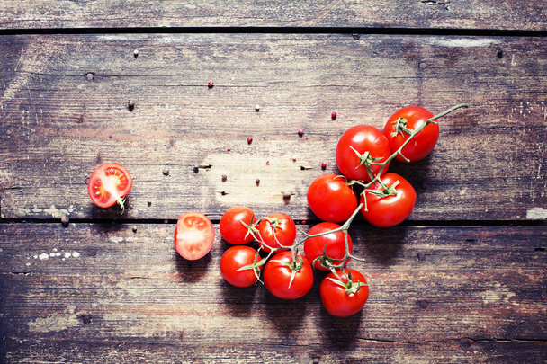 Appetizing branch of tomatoes on wooden table - Photo, Image
