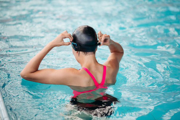青い水のプールで水泳キャップにスポーティな女性. - 写真・画像