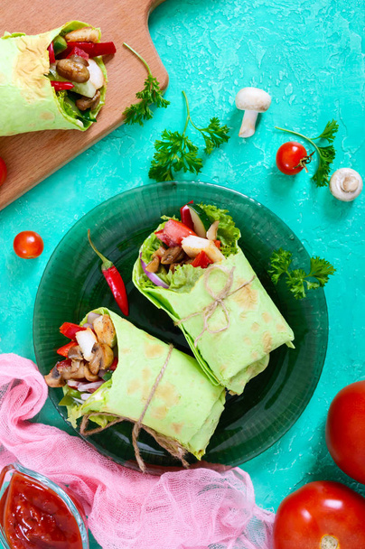 Burrito con pollo, verduras, champiñones en pan de pita con espinacas sobre una mesa de madera. Comida mexicana
. - Foto, Imagen