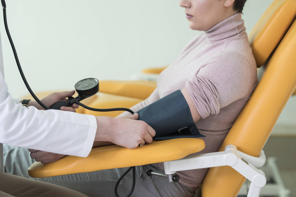 Руки невизначеної жінки-лікаря, що вимірює кров'яний тиск пацієнта в лікарні
. - Фото, зображення