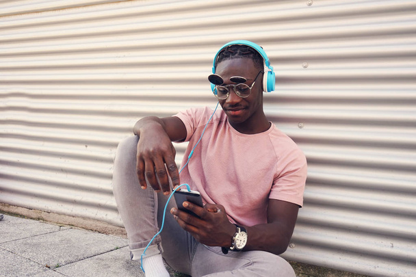Joven guapo con divertidas gafas de sol escuchando música con su smartphone - Foto, imagen