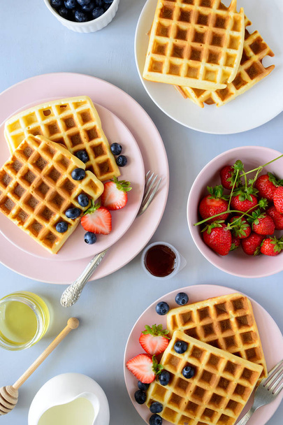 Belgian waffles with strawberries and honey on gray background. Healthy breakfast concept - Foto, afbeelding