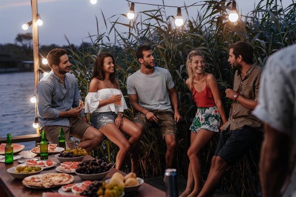 Group of young men and women enjoying summer holiday at outdoor party. - Fotoğraf, Görsel