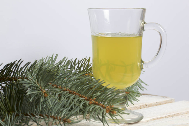 Blue spruce branches on a wooden box of boards, painted in white. Nearby is a glass of yellow liquor. - Photo, Image