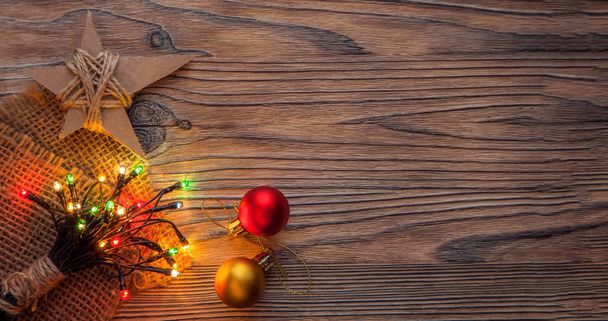 Kerst ster, lichte garland en kerstballen op houten achtergrond - Foto, afbeelding