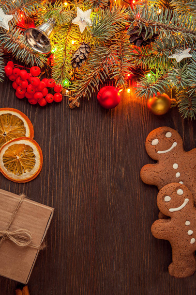 gingerbread cookies, gift box and Christmas tree with light garland on wooden table with copy space - Photo, Image